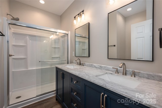 full bath with wood finished floors, a sink, and a shower stall