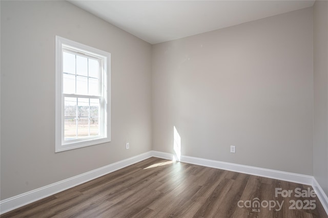 empty room featuring dark wood-style flooring and baseboards