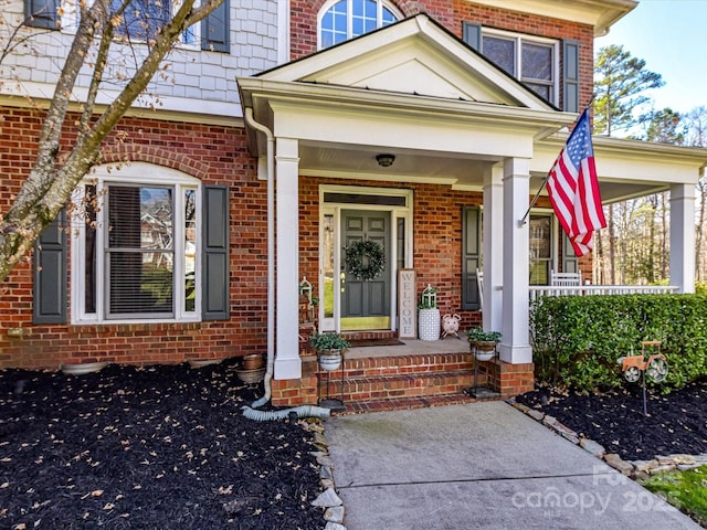 entrance to property featuring covered porch and brick siding