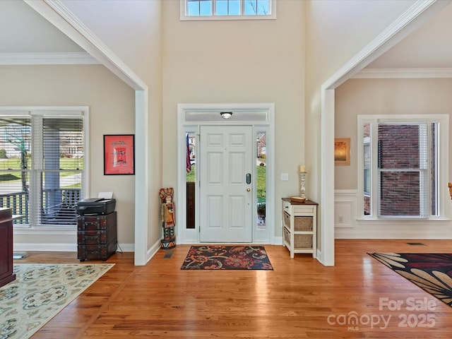 entrance foyer featuring a healthy amount of sunlight, crown molding, and wood finished floors