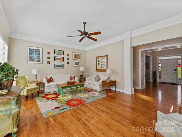 living room with ornamental molding, ceiling fan, baseboards, and wood finished floors