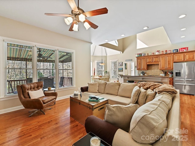 living area featuring light wood-style flooring, baseboards, and ceiling fan