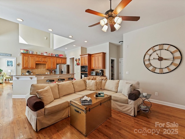 living room featuring a ceiling fan, recessed lighting, light wood-style flooring, and baseboards