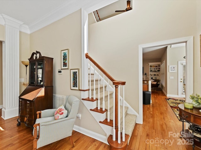 staircase with ornamental molding, wood finished floors, and baseboards