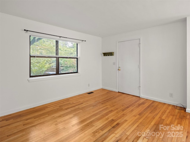 spare room featuring light wood-style floors, visible vents, and baseboards