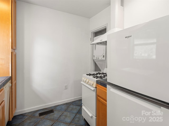 kitchen with tile counters, white appliances, visible vents, and baseboards