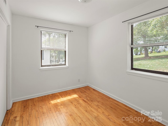 spare room with baseboards and light wood-style floors