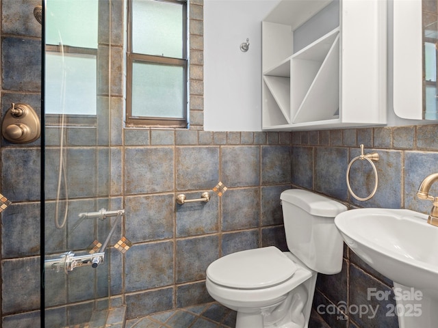 bathroom featuring toilet, a sink, and tile walls