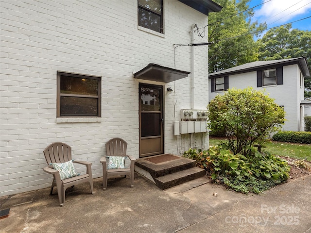 doorway to property featuring brick siding and a patio