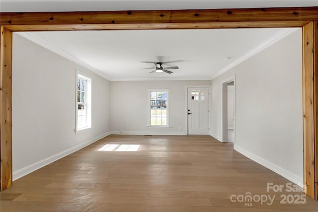 unfurnished living room with light wood-style floors, ceiling fan, baseboards, and crown molding