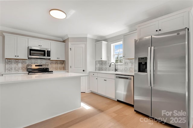 kitchen featuring light wood-style flooring, white cabinetry, stainless steel appliances, and light countertops