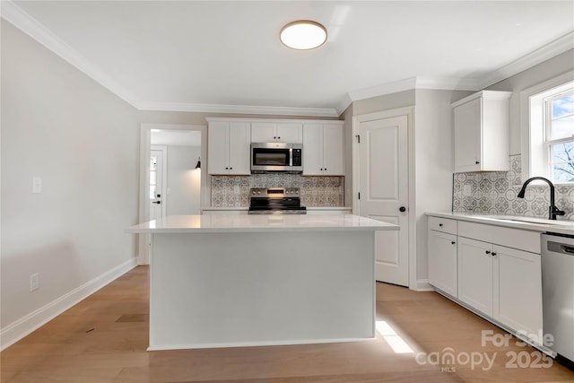 kitchen with a kitchen island, stainless steel appliances, light countertops, light wood-type flooring, and a sink