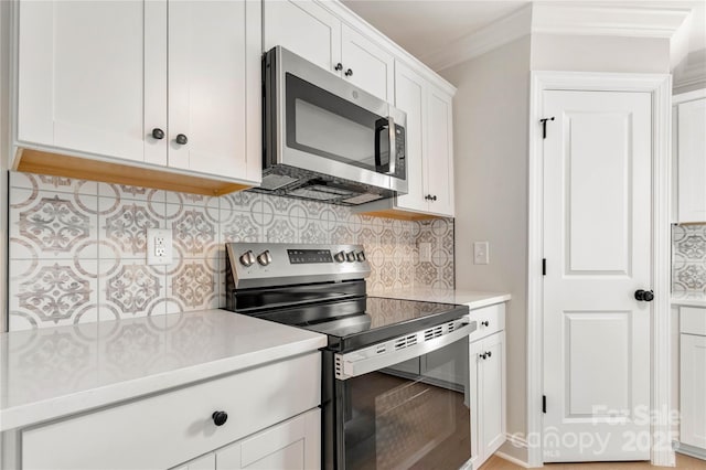 kitchen with decorative backsplash, appliances with stainless steel finishes, light countertops, crown molding, and white cabinetry