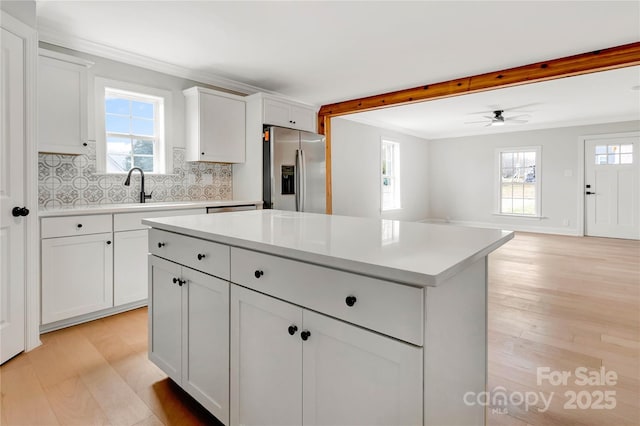 kitchen with light countertops, a sink, light wood-style flooring, and stainless steel fridge with ice dispenser