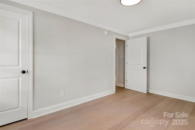 spare room featuring ornamental molding, baseboards, and wood finished floors