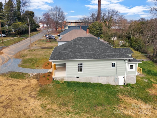 exterior space with a yard and roof with shingles