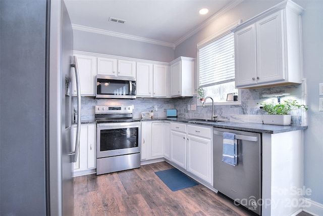 kitchen featuring visible vents, ornamental molding, a sink, stainless steel appliances, and white cabinets