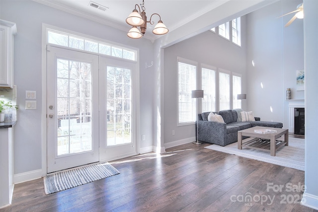 entryway featuring visible vents, crown molding, baseboards, an inviting chandelier, and wood finished floors