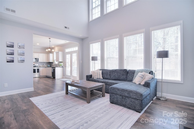 living room with visible vents, baseboards, a healthy amount of sunlight, and dark wood finished floors