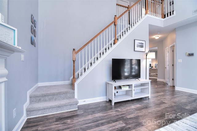 staircase featuring visible vents, wood finished floors, baseboards, and a towering ceiling