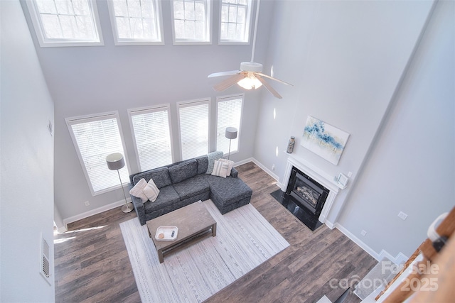 living room with a high ceiling, plenty of natural light, and dark wood-style floors