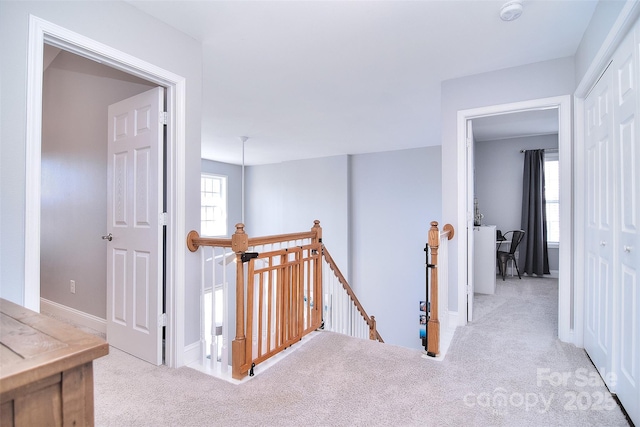 corridor featuring an upstairs landing, carpet flooring, and baseboards