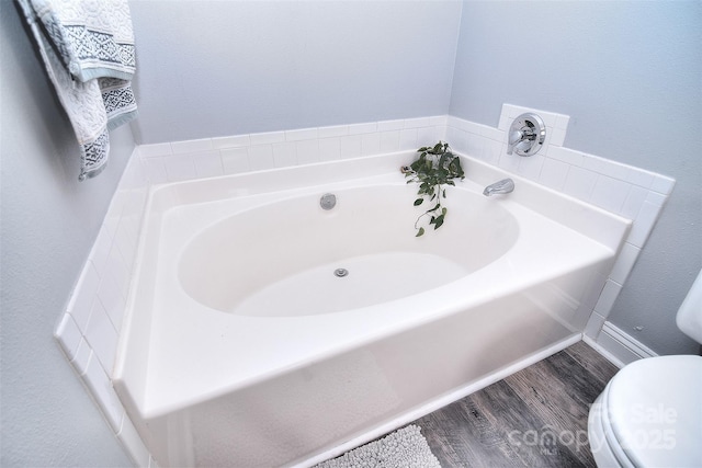 bathroom featuring toilet, a garden tub, and wood finished floors