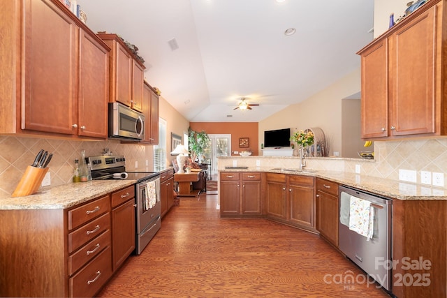 kitchen featuring visible vents, appliances with stainless steel finishes, a peninsula, vaulted ceiling, and a sink