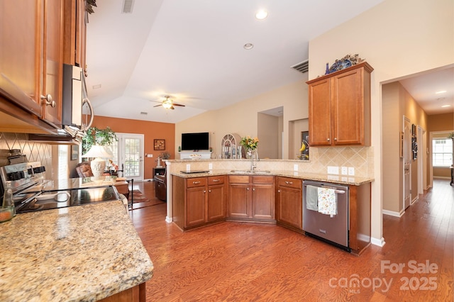 kitchen featuring a peninsula, appliances with stainless steel finishes, brown cabinetry, and a sink