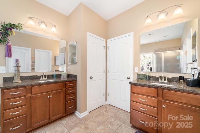 full bath featuring a stall shower, tile patterned flooring, two vanities, and a sink