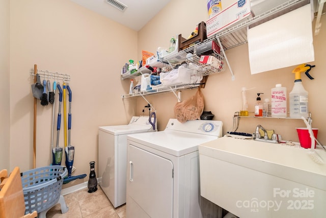 clothes washing area with visible vents, light tile patterned flooring, a sink, laundry area, and independent washer and dryer