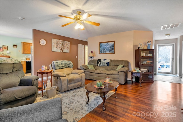 living room featuring baseboards, wood finished floors, visible vents, and ceiling fan