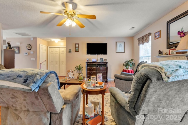 living area with baseboards, wood finished floors, visible vents, and ceiling fan