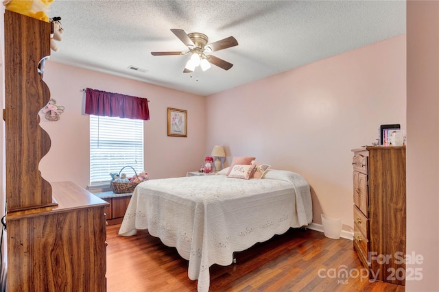 bedroom with a ceiling fan, wood finished floors, baseboards, and a textured ceiling