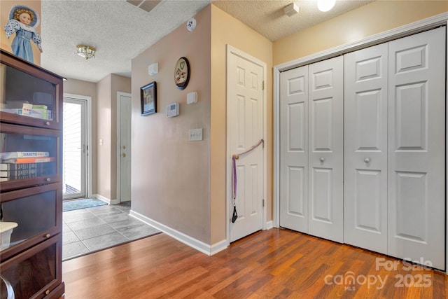 foyer with a textured ceiling, baseboards, and wood finished floors