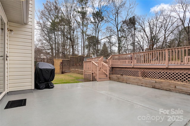 view of patio featuring visible vents, a wooden deck, a grill, and fence