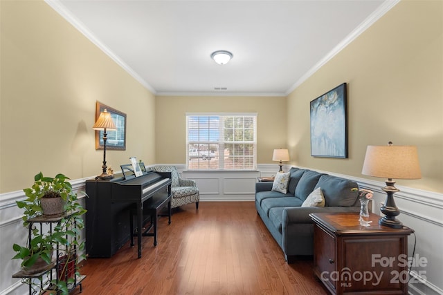 living area with ornamental molding, wainscoting, visible vents, and wood finished floors