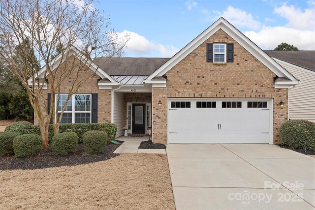 traditional home featuring concrete driveway, metal roof, roof with shingles, an attached garage, and brick siding