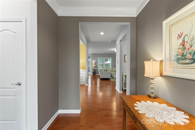 hallway featuring baseboards, ornamental molding, and wood finished floors