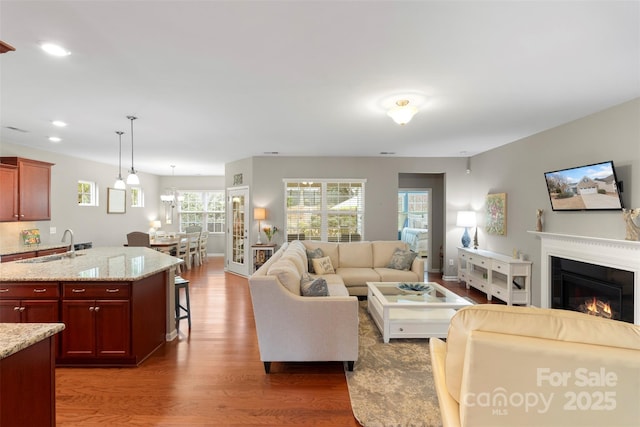 living area featuring a glass covered fireplace, recessed lighting, and wood finished floors