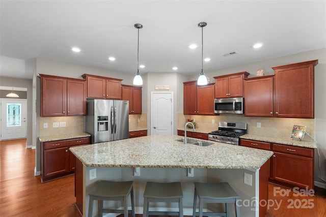 kitchen with a breakfast bar area, visible vents, appliances with stainless steel finishes, dark wood-type flooring, and a sink