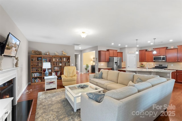 living area featuring a lit fireplace, baseboards, dark wood-style flooring, and recessed lighting