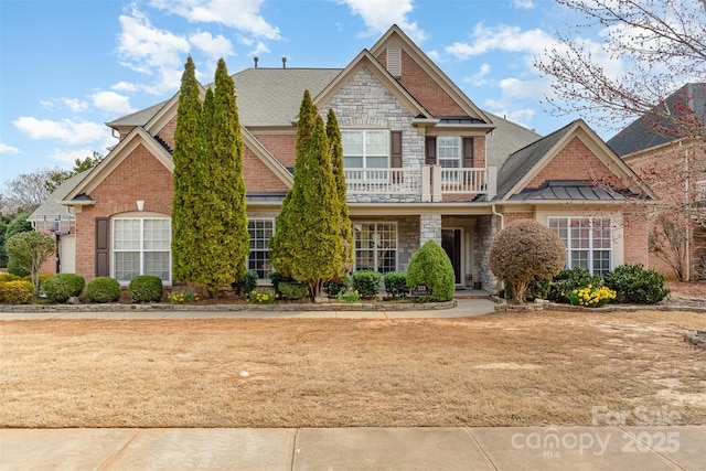 view of front of property featuring a balcony, stone siding, roof with shingles, and brick siding