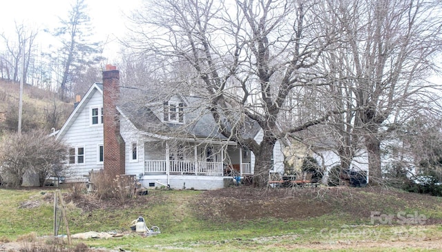 cape cod home with a porch, a chimney, and a shingled roof