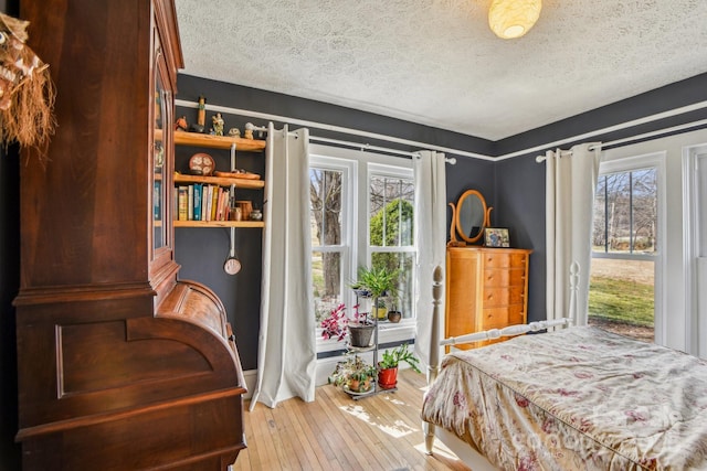 bedroom with baseboards, wood-type flooring, and a textured ceiling