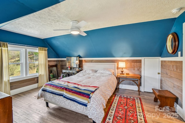 bedroom featuring ceiling fan, a textured ceiling, wood finished floors, and vaulted ceiling