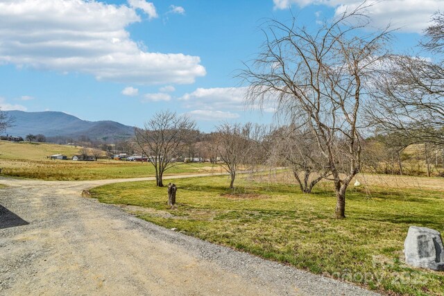 view of community with a mountain view, a yard, driveway, and a rural view