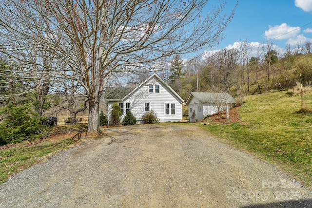 view of front of property featuring an outdoor structure, a front lawn, and driveway