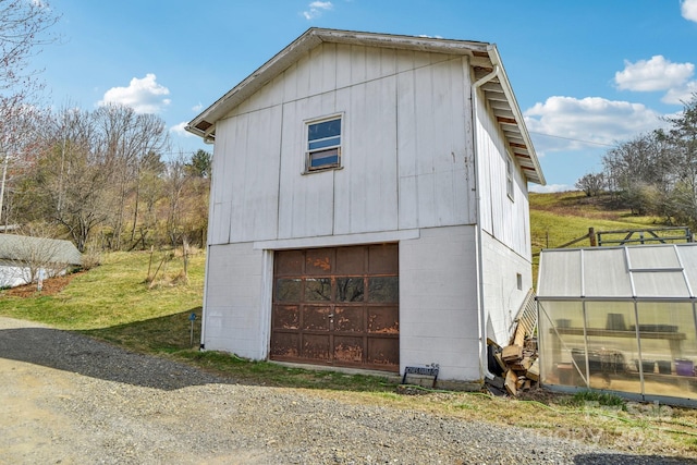 view of home's exterior featuring a detached garage, an outbuilding, concrete block siding, and driveway