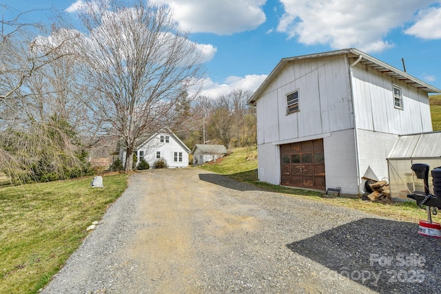 view of property exterior with gravel driveway, an outbuilding, a yard, and a detached garage